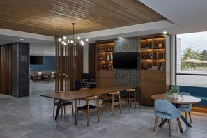 Una sala de conferencias moderna con una mesa larga, sillas, una televisión y una estantería con diversos objetos.