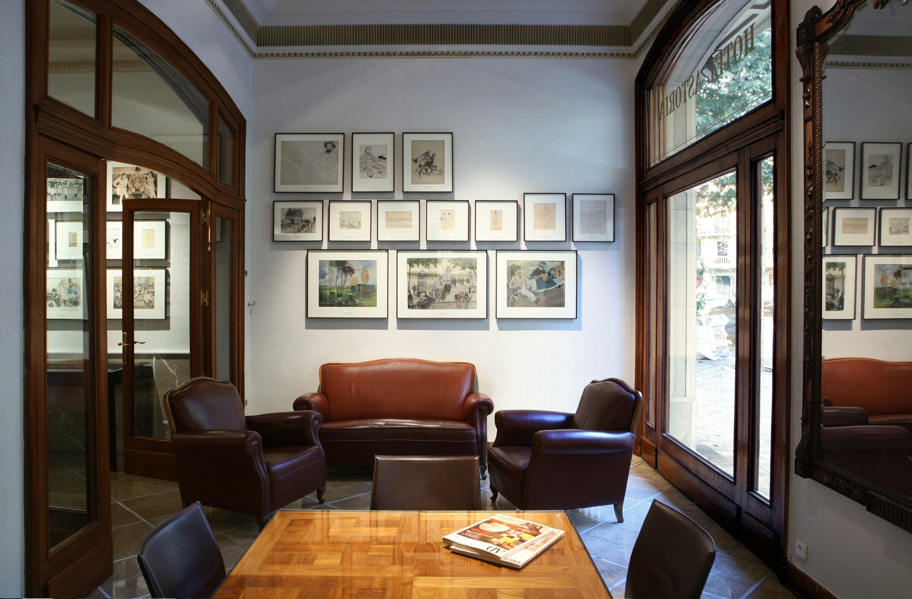 Una habitación con una mesa de madera, sillas de cuero, un sofá y cuadros en las paredes.