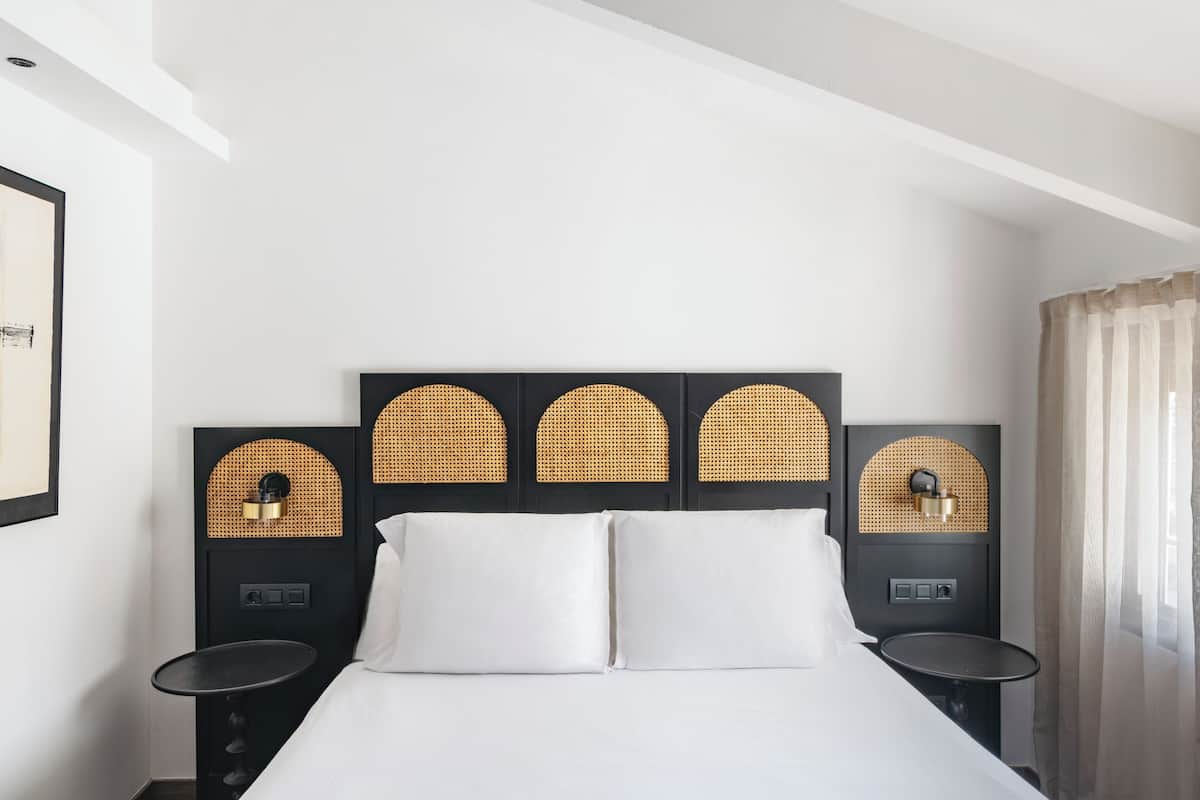 Een hotelkamer met een bed, twee nachtkastjes en een hoofdbord met een geweven ontwerp.