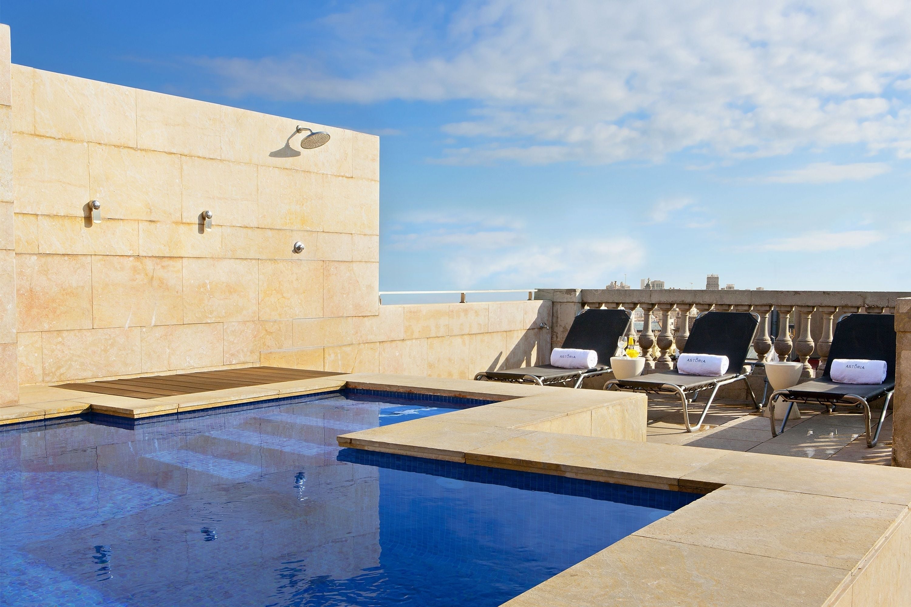 Een seizoensgebonden buitenzwembad, ligstoelen bij het zwembad