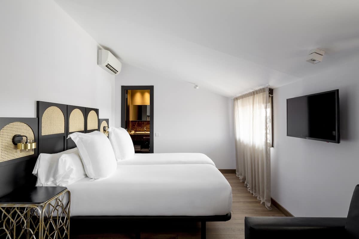Een moderne hotelkamer met een groot bed, een aan de muur bevestigde televisie en een zithoek met een fauteuil.