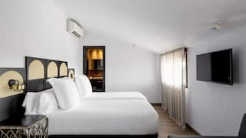 Una habitación de hotel moderna con una cama grande, un televisor montado en la pared y una zona de estar con una silla.
