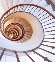 A spiral staircase with a wooden handrail and white steps.