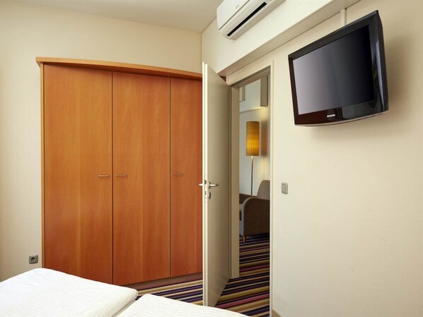 Une chambre d’hôtel comprenant un lit, une armoire, un téléviseur et une porte donnant sur une salle de bain.