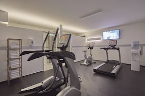 Un gimnasio con cintas de correr, elípticas y un dispensador de agua.