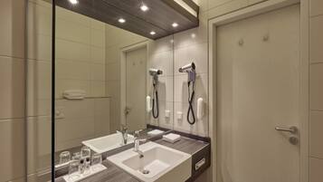 Un baño moderno con dos lavamanos, un espejo grande y secadores de pelo integrados.