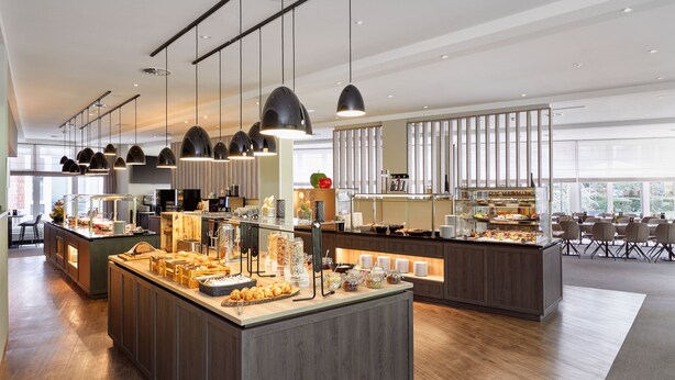 Una barra de desayuno moderna con diversos alimentos y una zona de estar con mesas y sillas.