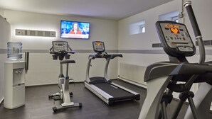 Un gimnasio con cintas de correr, elíptica y dispensador de agua.