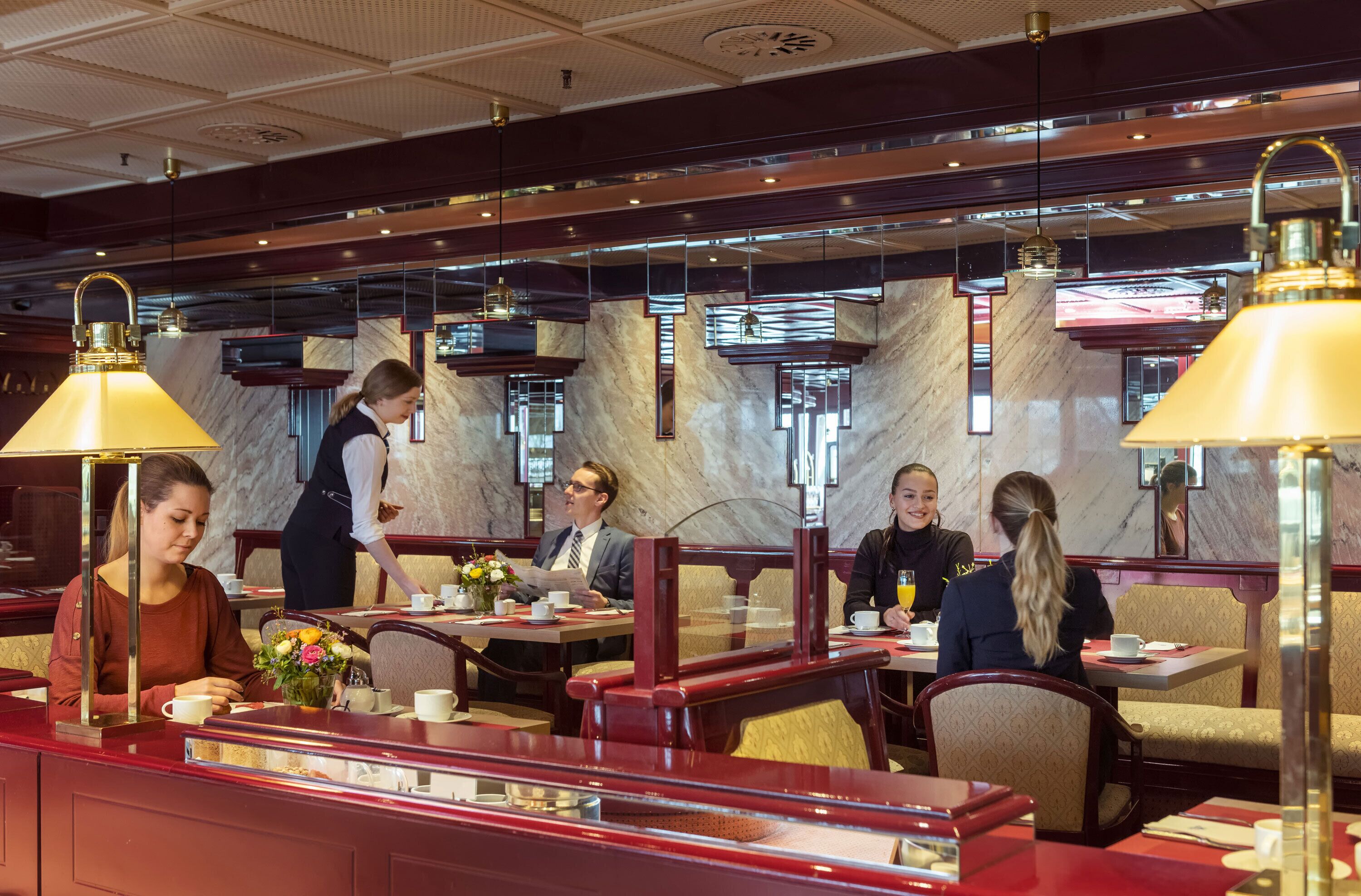 Un restaurante con paredes de mármol, cabinas rojas y lámparas colgantes.
