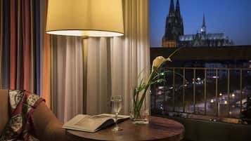 Habitación de hotel con vista a un paisaje urbano y una catedral al anochecer.