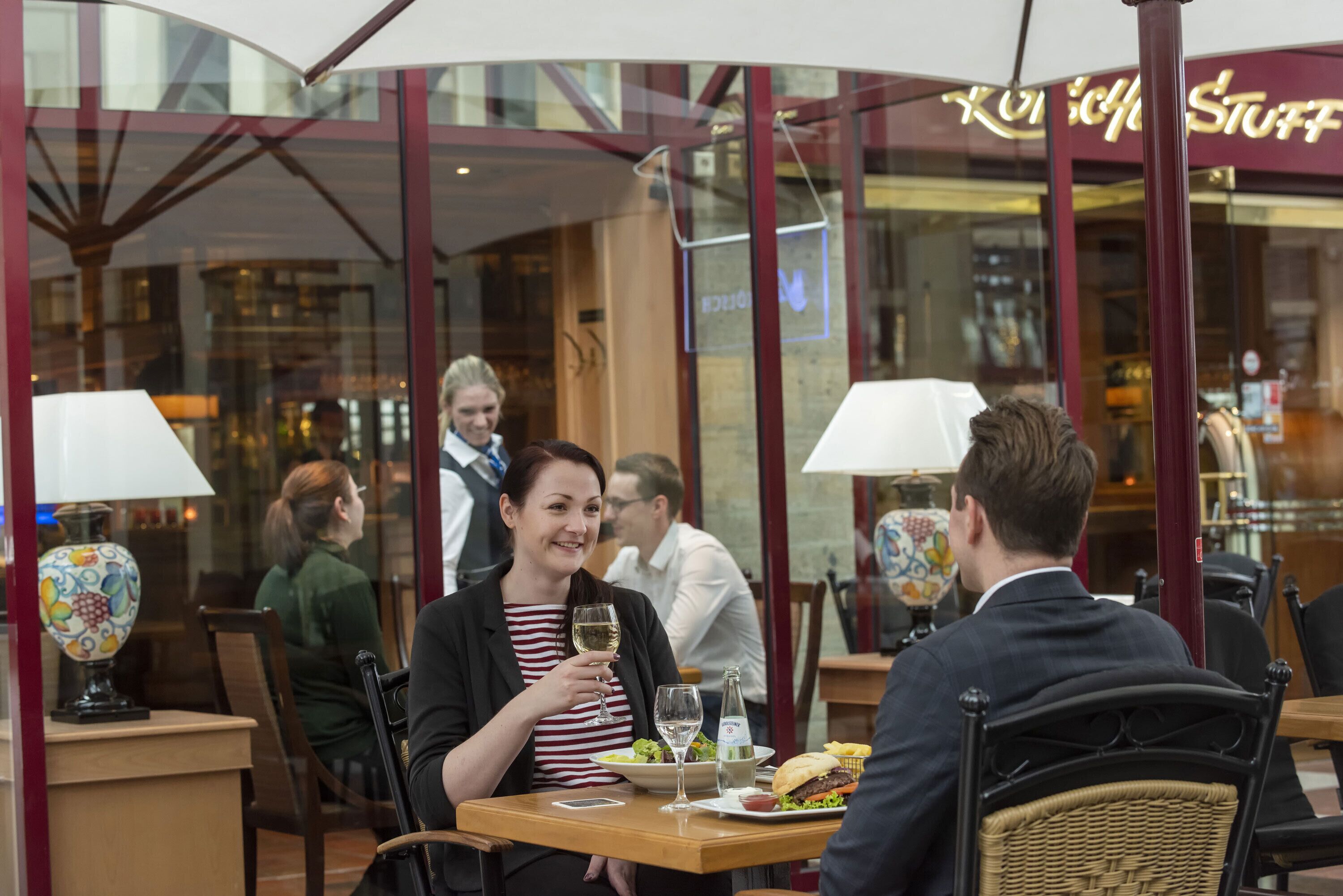 Un restaurant doté d’une façade en verre, de tables et de chaises en bois.