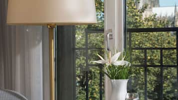 Ein Zimmer mit Tisch, Lampe, Blumenvase und Blick auf ein Dom.