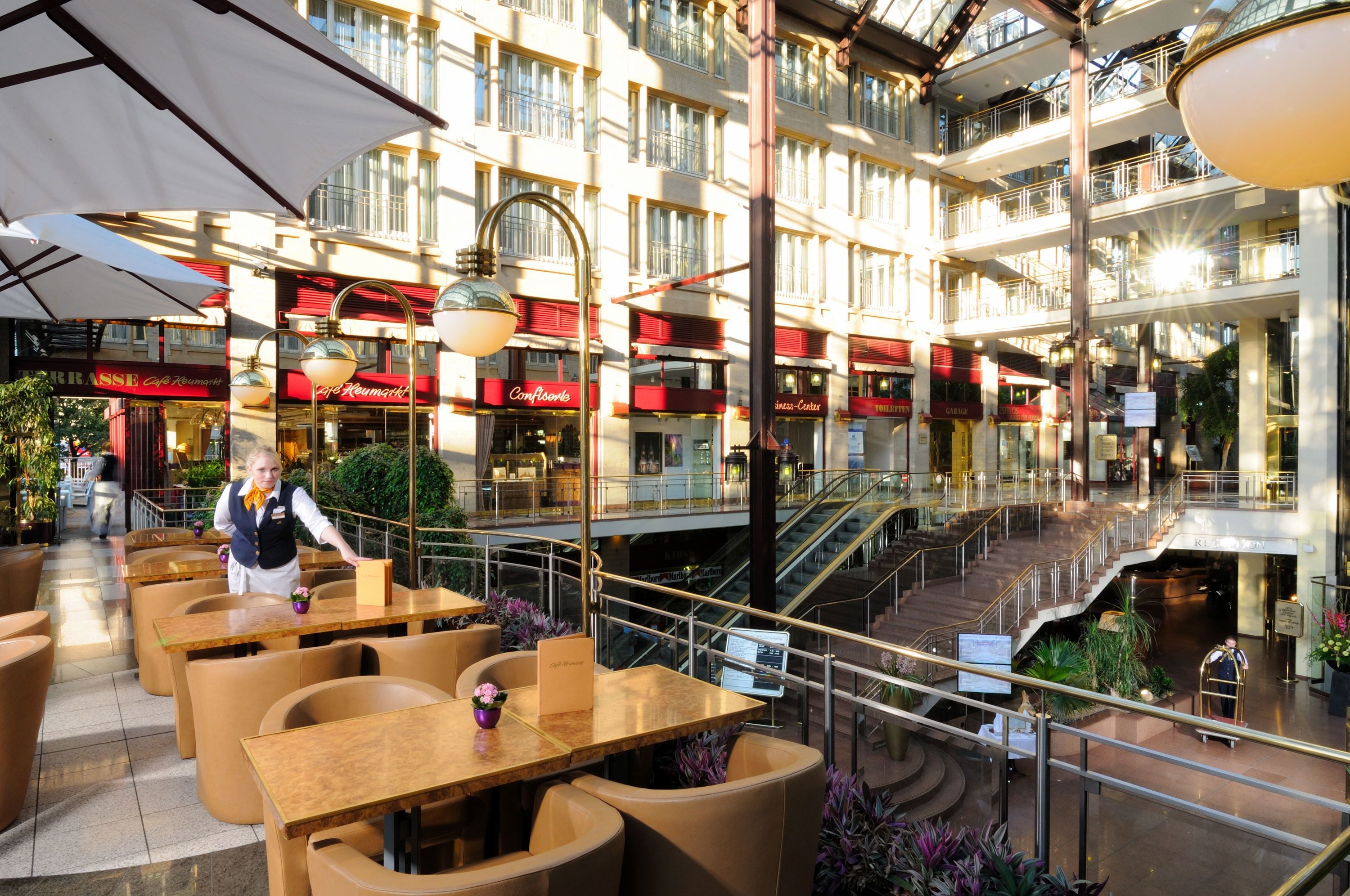 Een meerlaags atrium met eetgedeeltes, een centrale trap en diverse balkons.