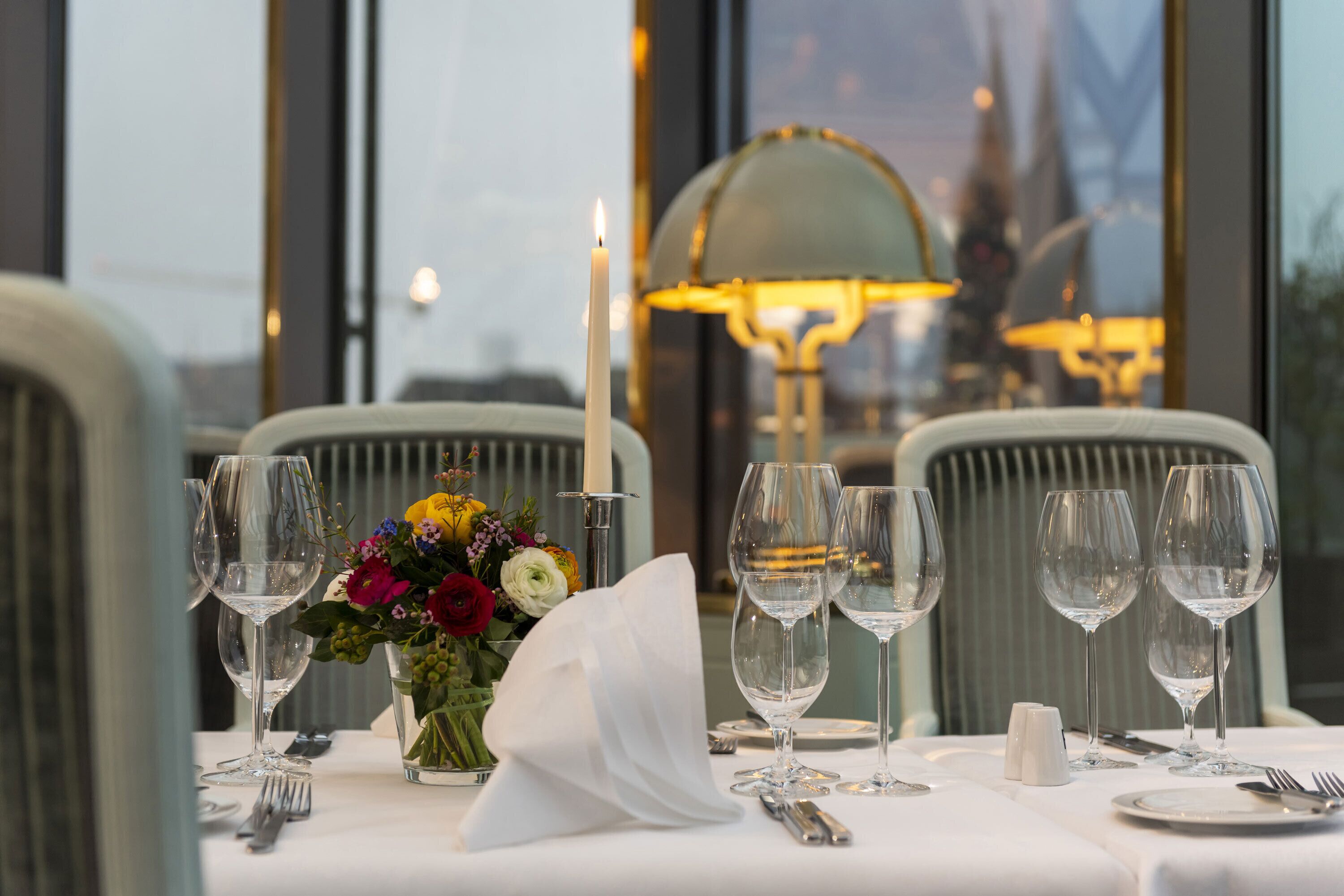 A table set for dining with clear glassware, a candle, and a floral centerpiece.