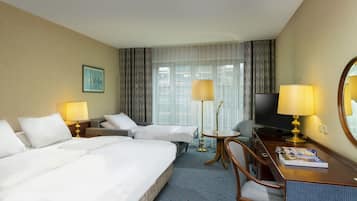 A hotel room with a large bed, a desk with a chair, a television, and two lamps.