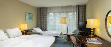 Ein Hotelzimmer mit einem großen Bett, einem Schreibtisch mit Stuhl, einem Fernseher und zwei Lampen.