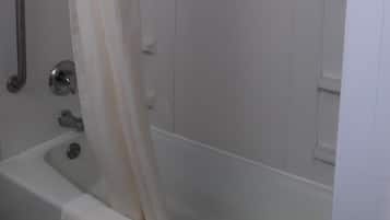 Une salle de bain avec une baignoire, un rideau de douche et une barre d’appui.