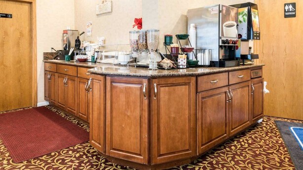 Een hotelkeuken met een centraal eiland, houten keukenkastjes en diverse keukenapparaten.