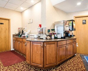 A hotel kitchen with a central island, wooden cabinets, and various kitchen appliances. - Rodeway Inn (Weedsport)