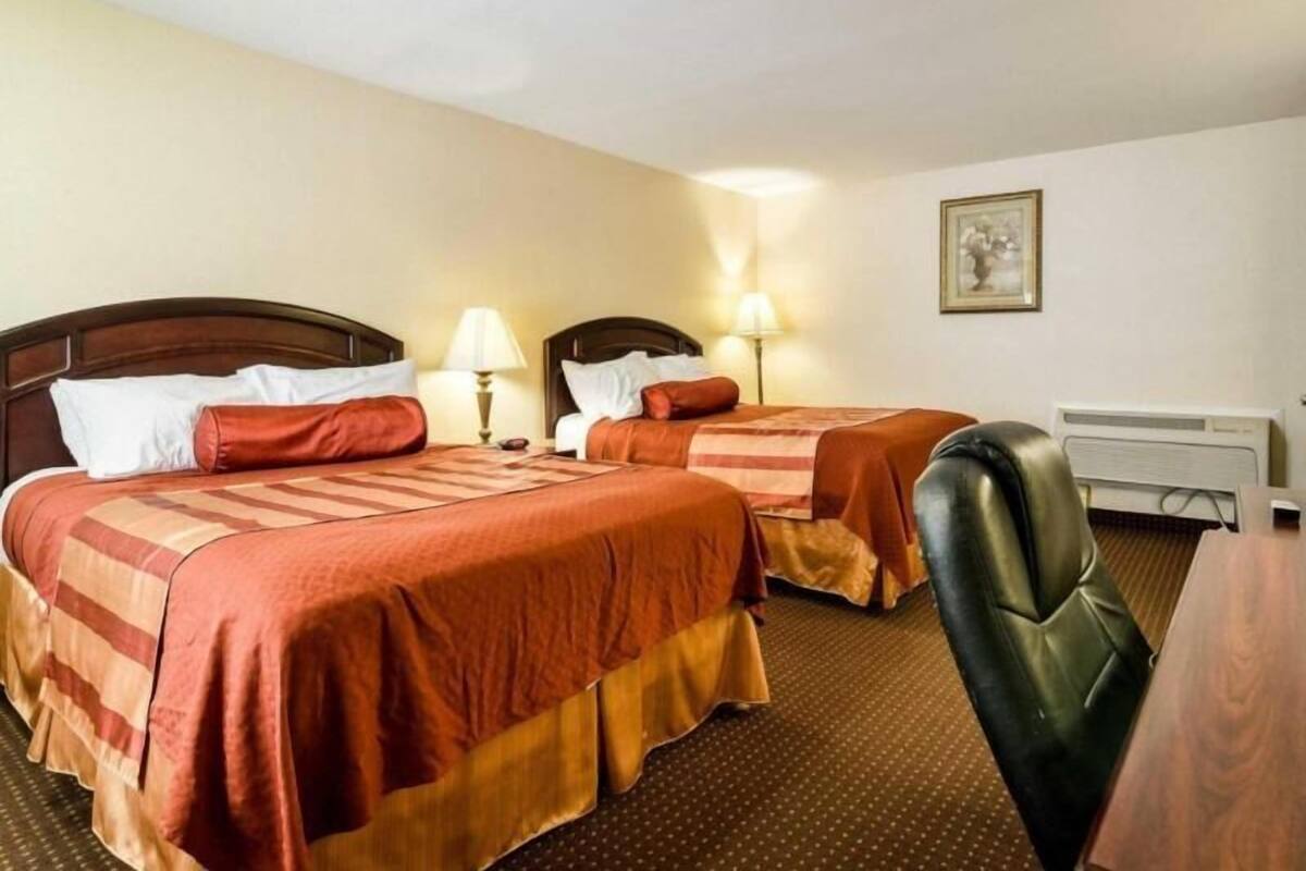 Ett hotellrum med två sängar, ett skrivbord och en stol.
