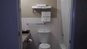 A small, compact bathroom with a toilet, a towel rack, and a shower area.