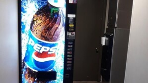 Een automaat met een Pepsi-reclame in een smalle gang.