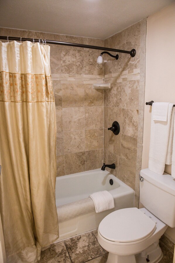 Un baño con bañera, inodoro y cortina de ducha.