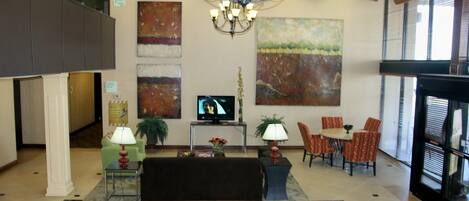 Un vestíbulo con una araña, obras de arte en las paredes, un televisor, zona de estar y una mesa de comedor.
