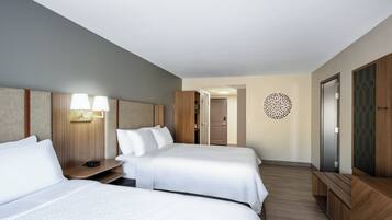 Habitación de hotel con dos camas, un escritorio, un armario y un adorno en la pared.