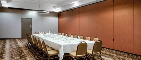 A conference room with a long table, chairs, and a patterned carpet.