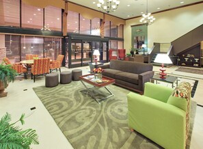 A spacious living area with a sofa, armchairs, a coffee table, and a dining set. - Holiday Inn Blytheville by IHG (Blytheville)