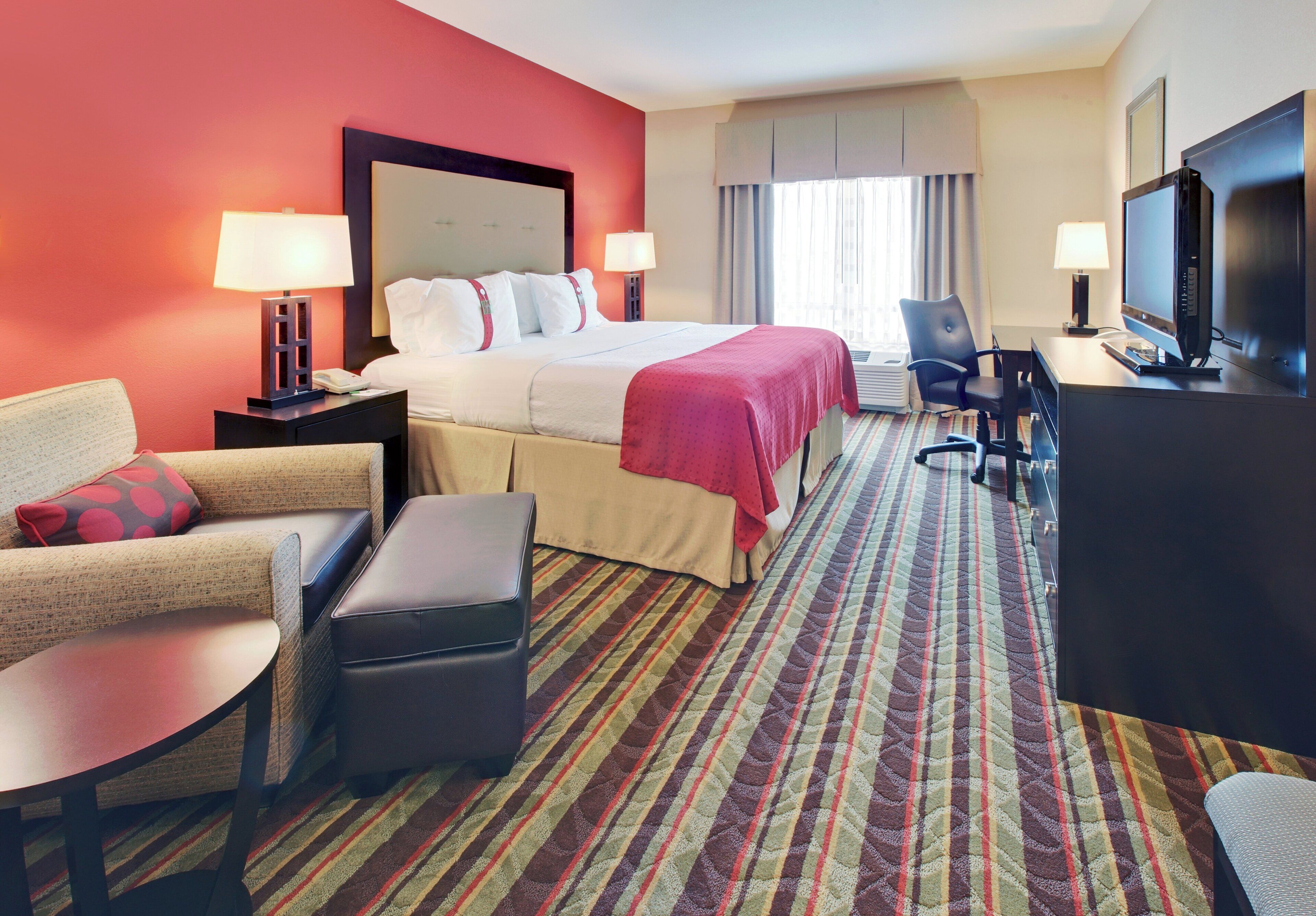 Een hotelkamer met een bed, bureau, televisie, stoel en bank.