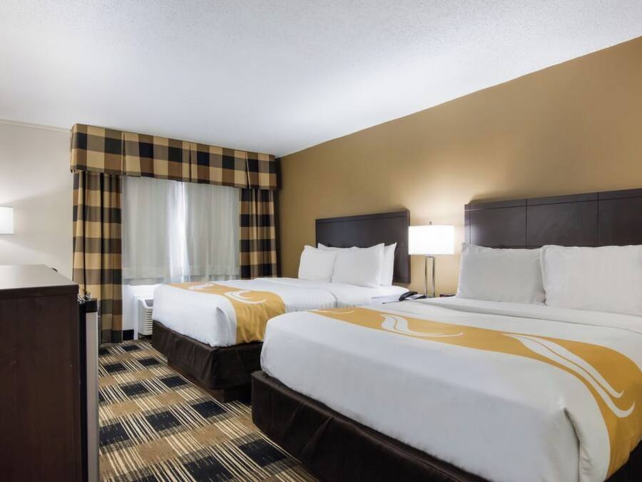 A hotel room with two beds, a desk, and a television.