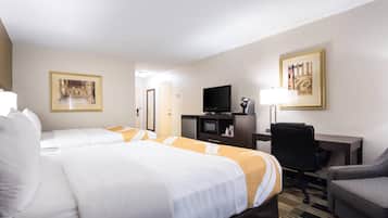 Habitación de hotel con dos camas, un escritorio, un televisor y una silla.