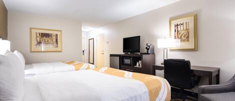 A hotel room with two beds, a desk, a television, and a chair.