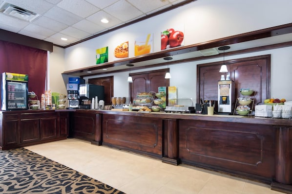 A hotel reception area with a counter, various food items, and a refrigerator. - Quality Inn Oneonta Cooperstown Area (Oneonta)