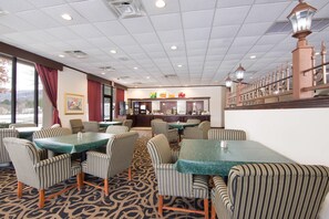 A hotel lobby with striped chairs and tables, a bar area, and a patterned carpet. - Quality Inn Oneonta Cooperstown Area (Oneonta)
