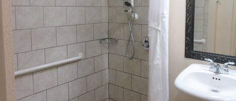 Un bagno con doccia, lavandino e specchio.
