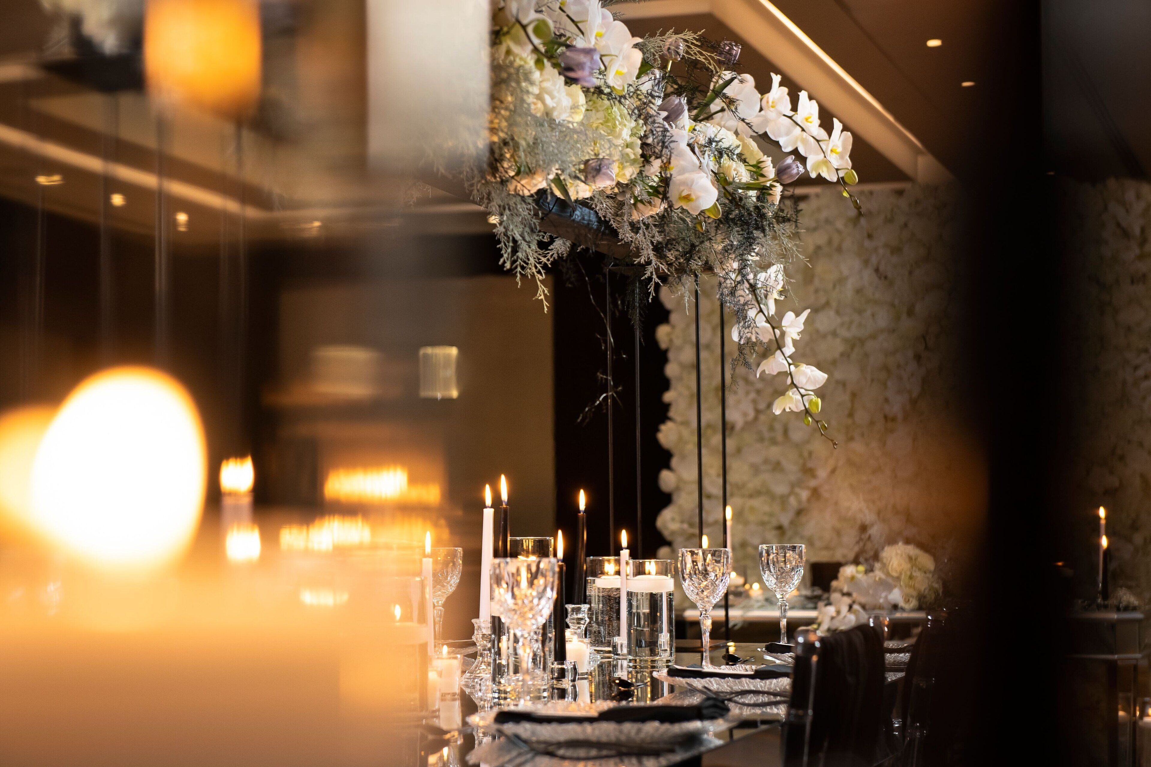 Un comedor bien iluminado con mesas preparadas para una comida, con velas y elegantes arreglos de mesa.