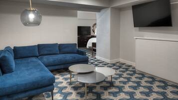 Una sala de estar moderna con un sofá seccional azul, dos mesas de centro redondas y una alfombra estampada.