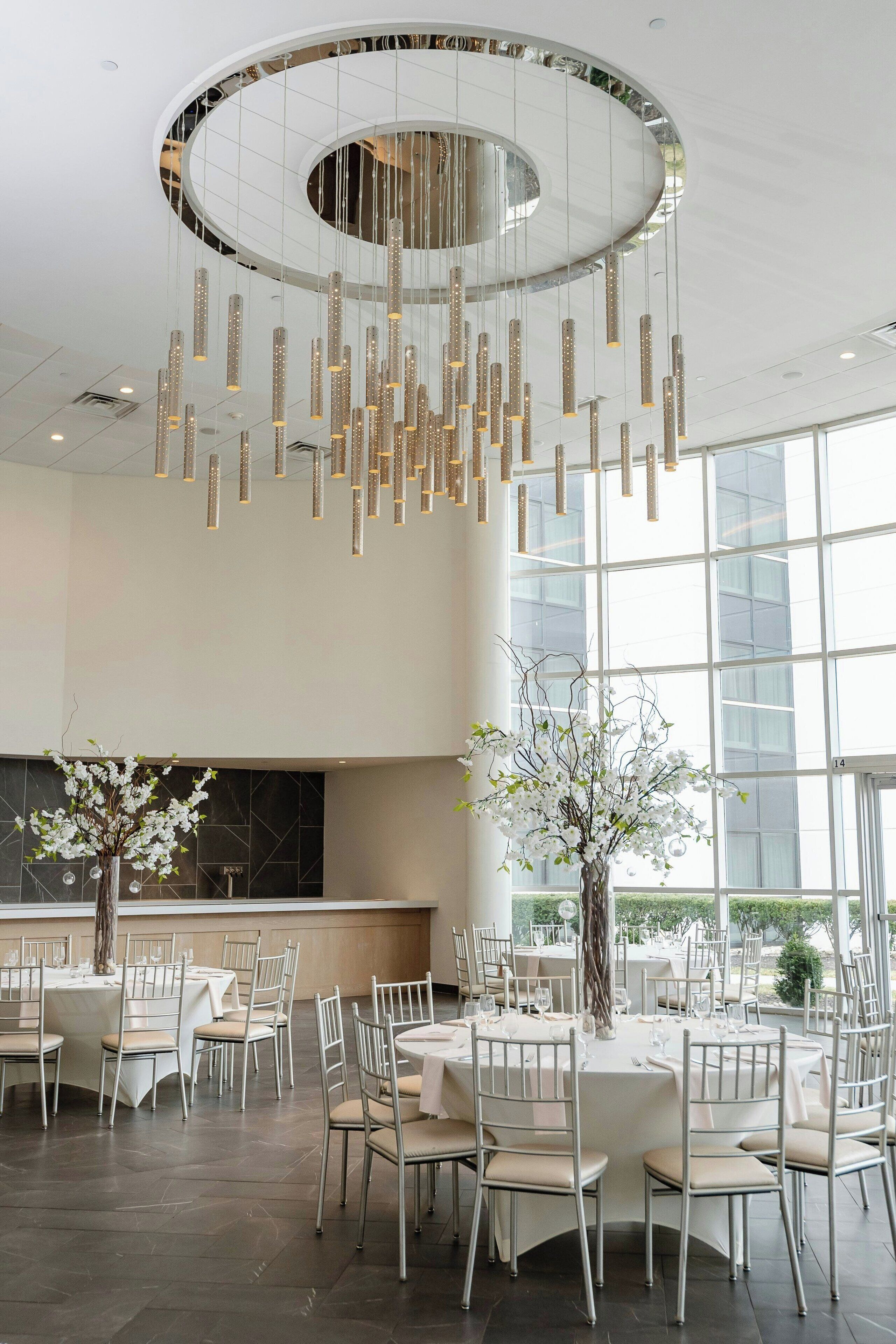 Un espace de restauration moderne avec des tables rondes, des chaises blanches et des luminaires suspendus.