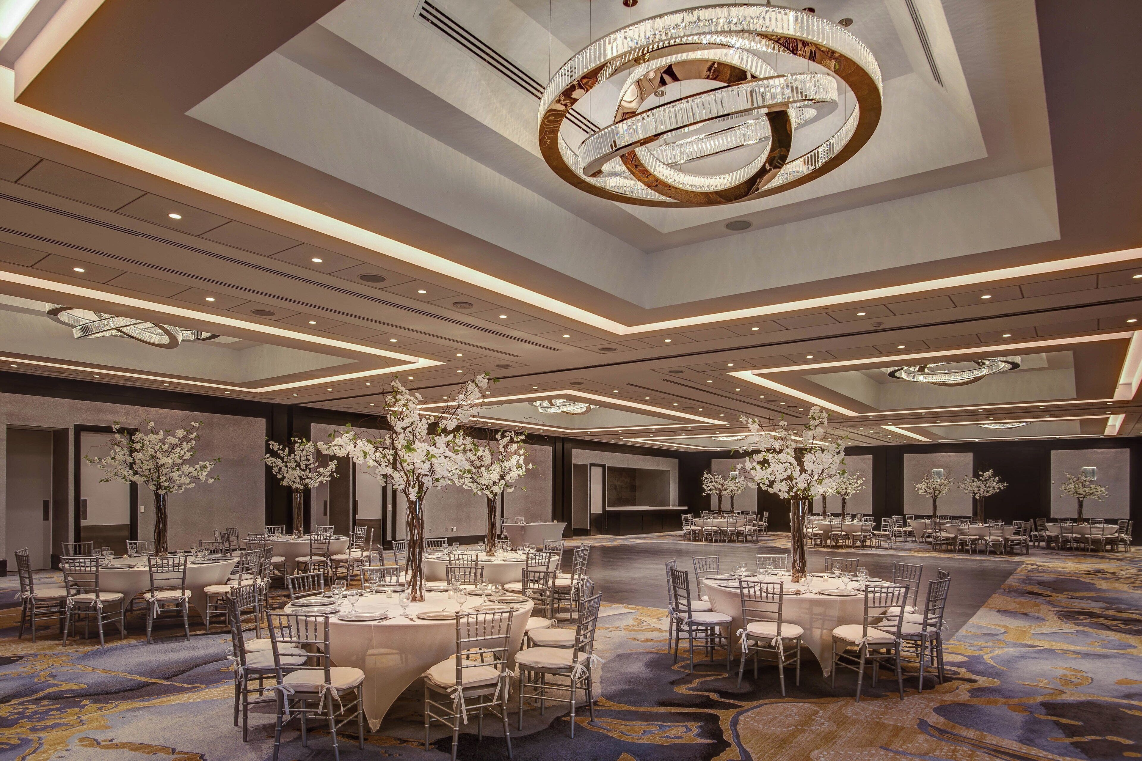 Un amplio salón de banquetes con mesas redondas, candelabros elegantes y centros de mesa florales.