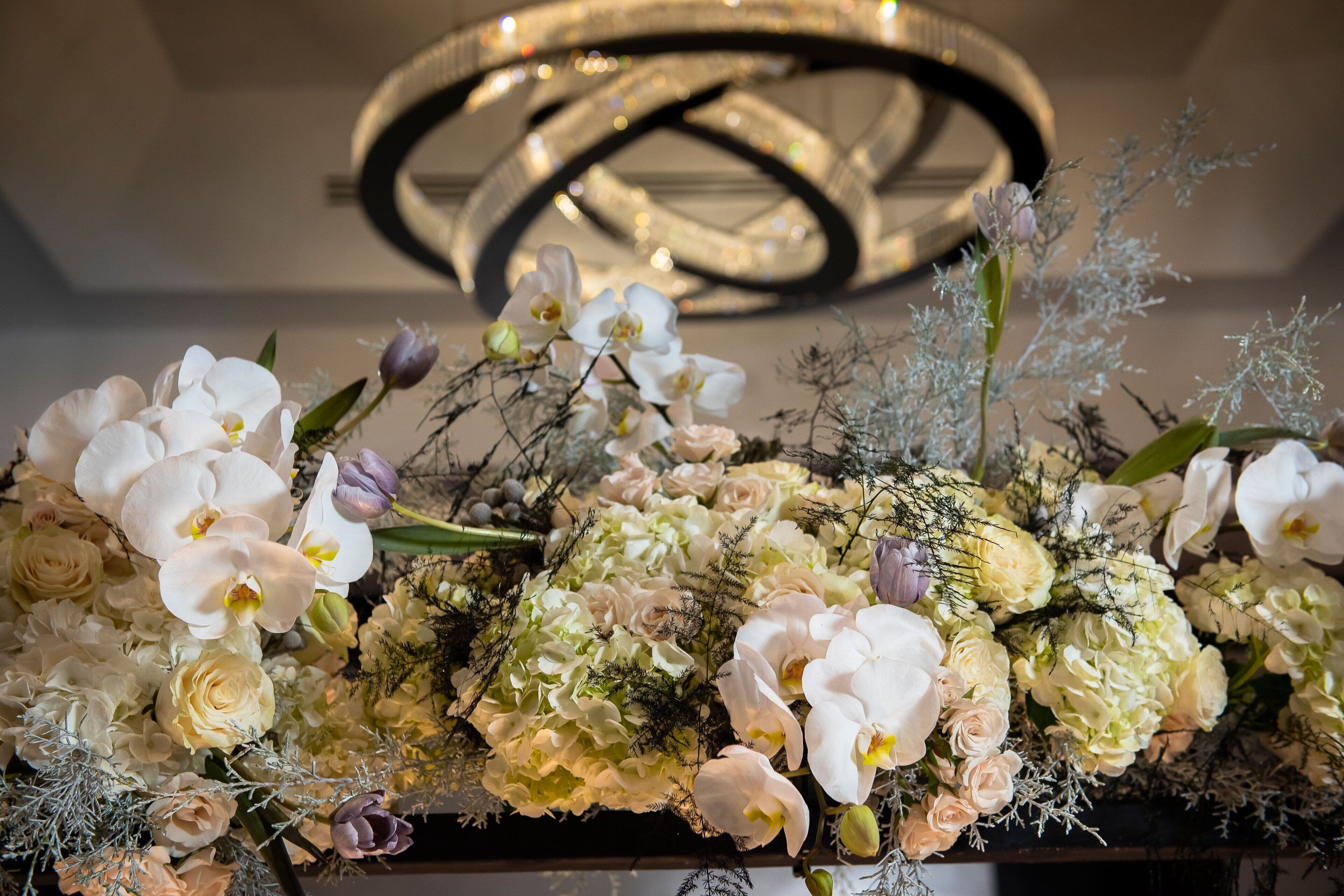 A floral arrangement with white and pink flowers, including orchids and roses, in a decorative setting.