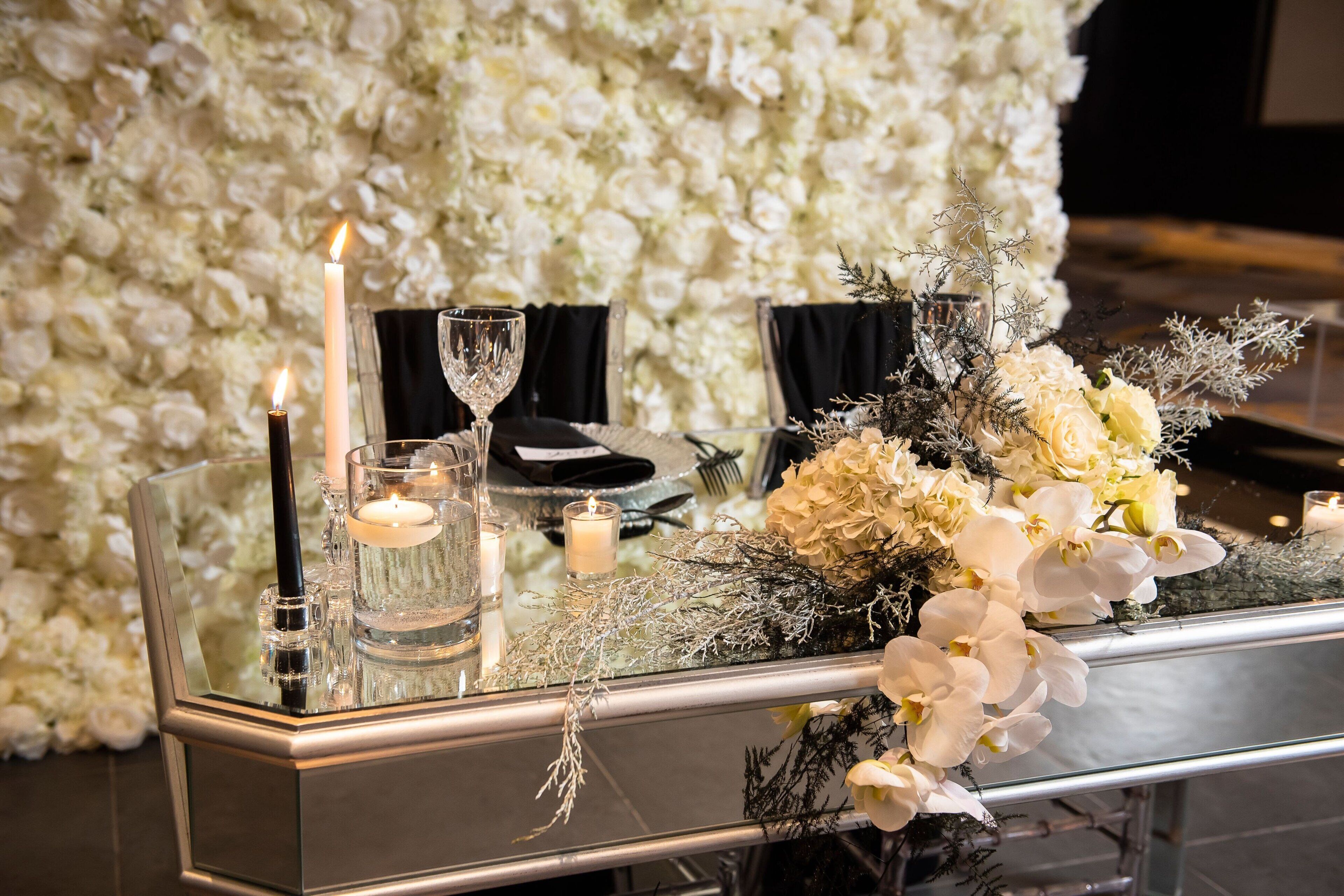 A table set with candles, a glass, and a floral arrangement.