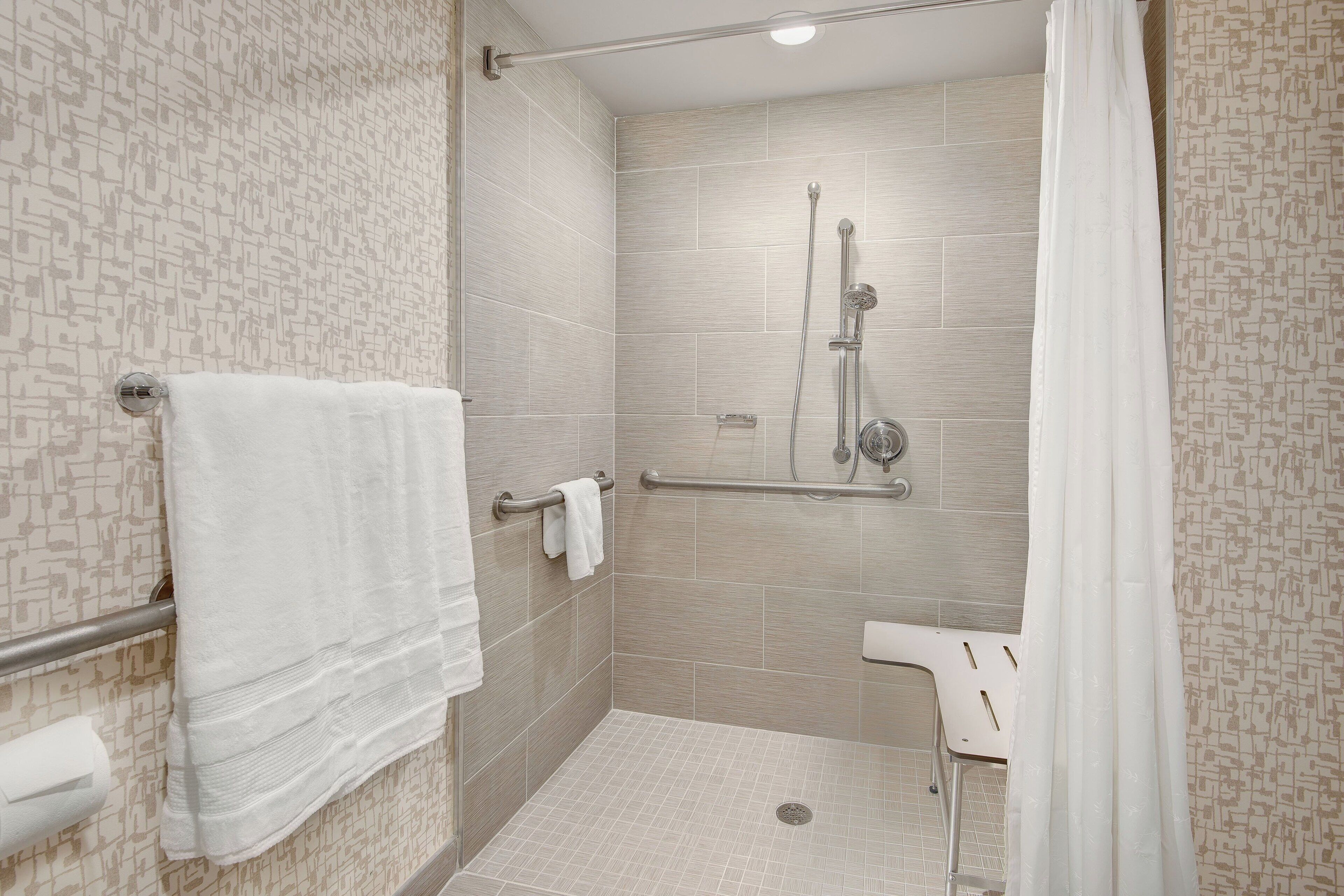 A shower area with a handrail, a towel rack, and a toilet.