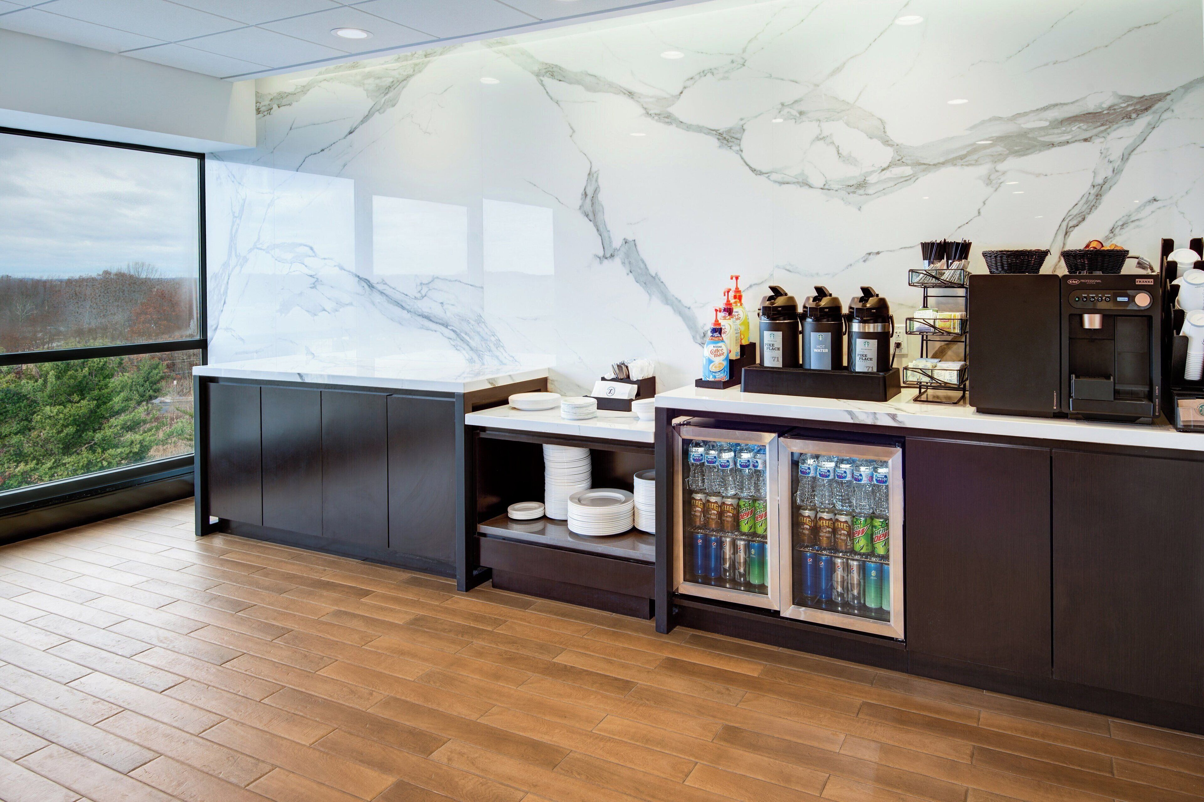 Un espace bar moderne avec des murs en marbre, un distributeur de boissons réfrigéré et une machine à café.