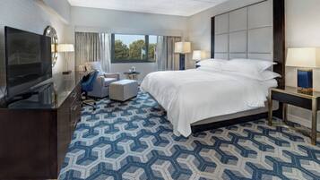 Une chambre d’hôtel avec un grand lit, une télévision, un bureau et une chaise.