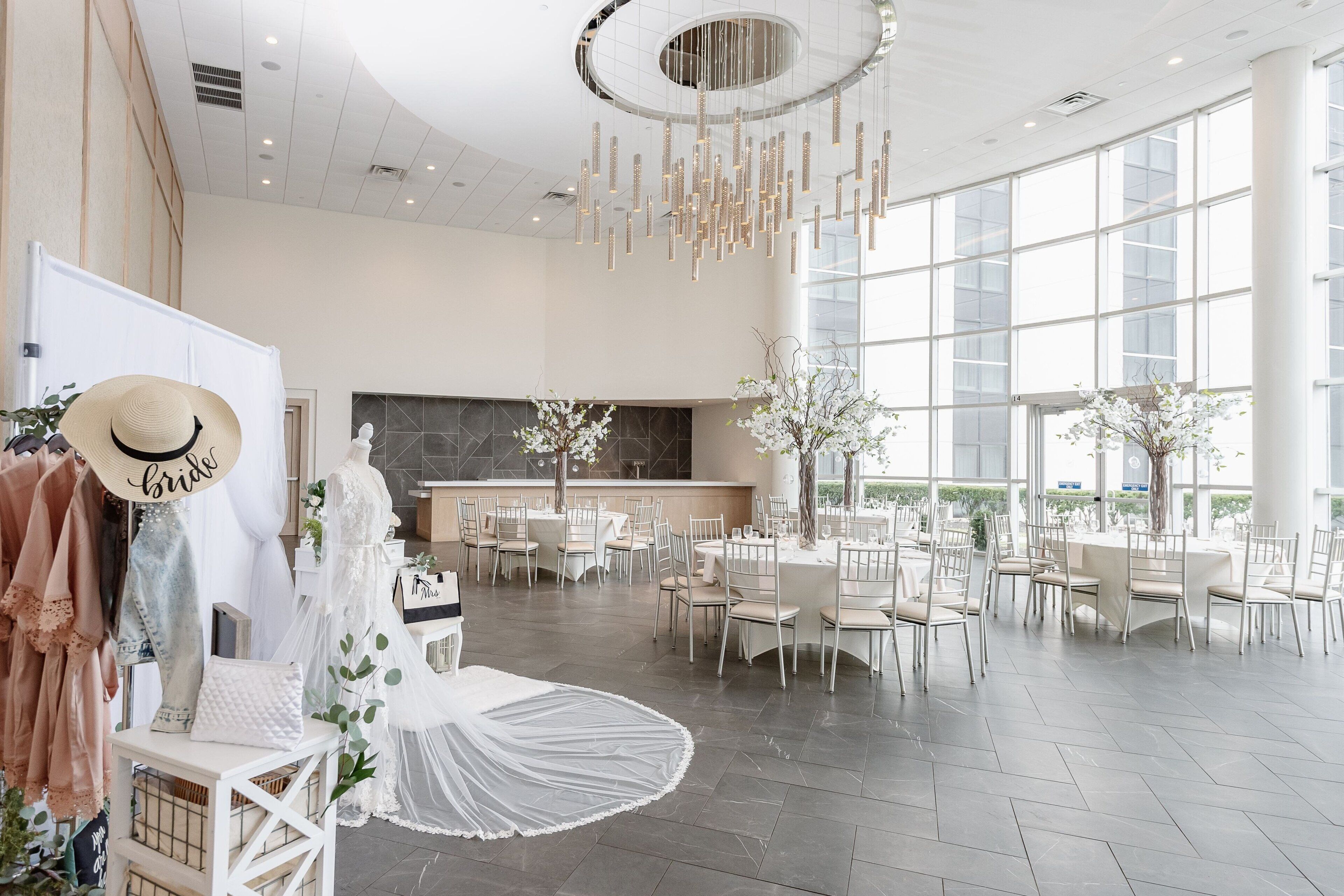 A spacious hall with a high ceiling, large windows, and a central seating area with round tables and chairs.