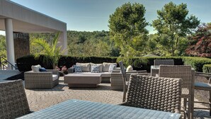 Un área de patio al aire libre con mobiliario de mimbre, incluyendo sofás y sillones, y piso de baldosas.