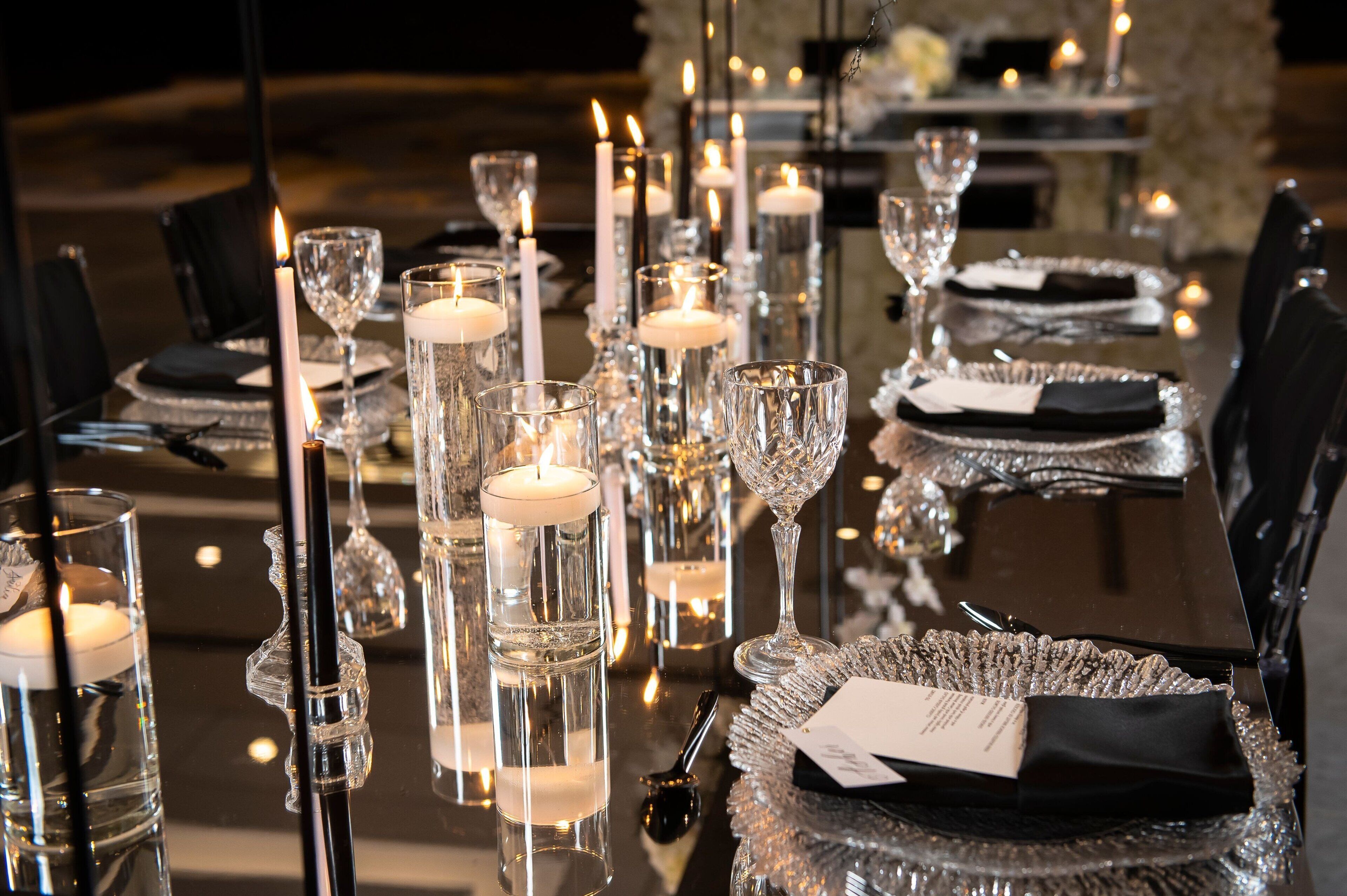 A table set with crystal glassware, candles, and black napkins.